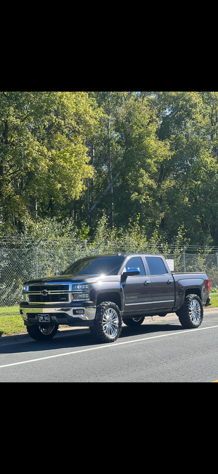 Detailed lifted Silverado parked roadside with chrome wheels shining